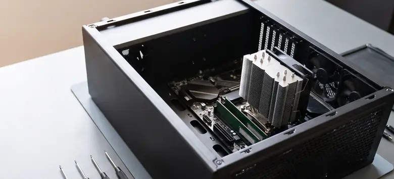 Gabinete de PC abierto con placa madre, memorias y disipador sobre una mesa de armado, con destornilladores de precisión