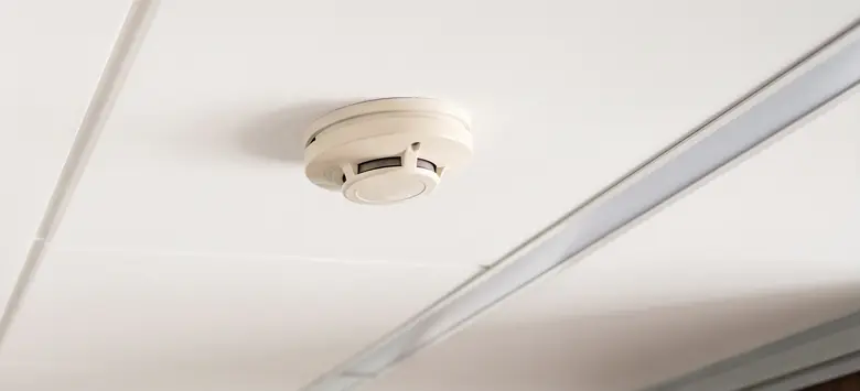 Detector de humo blanco instalado en el techo de un pasillo de oficina